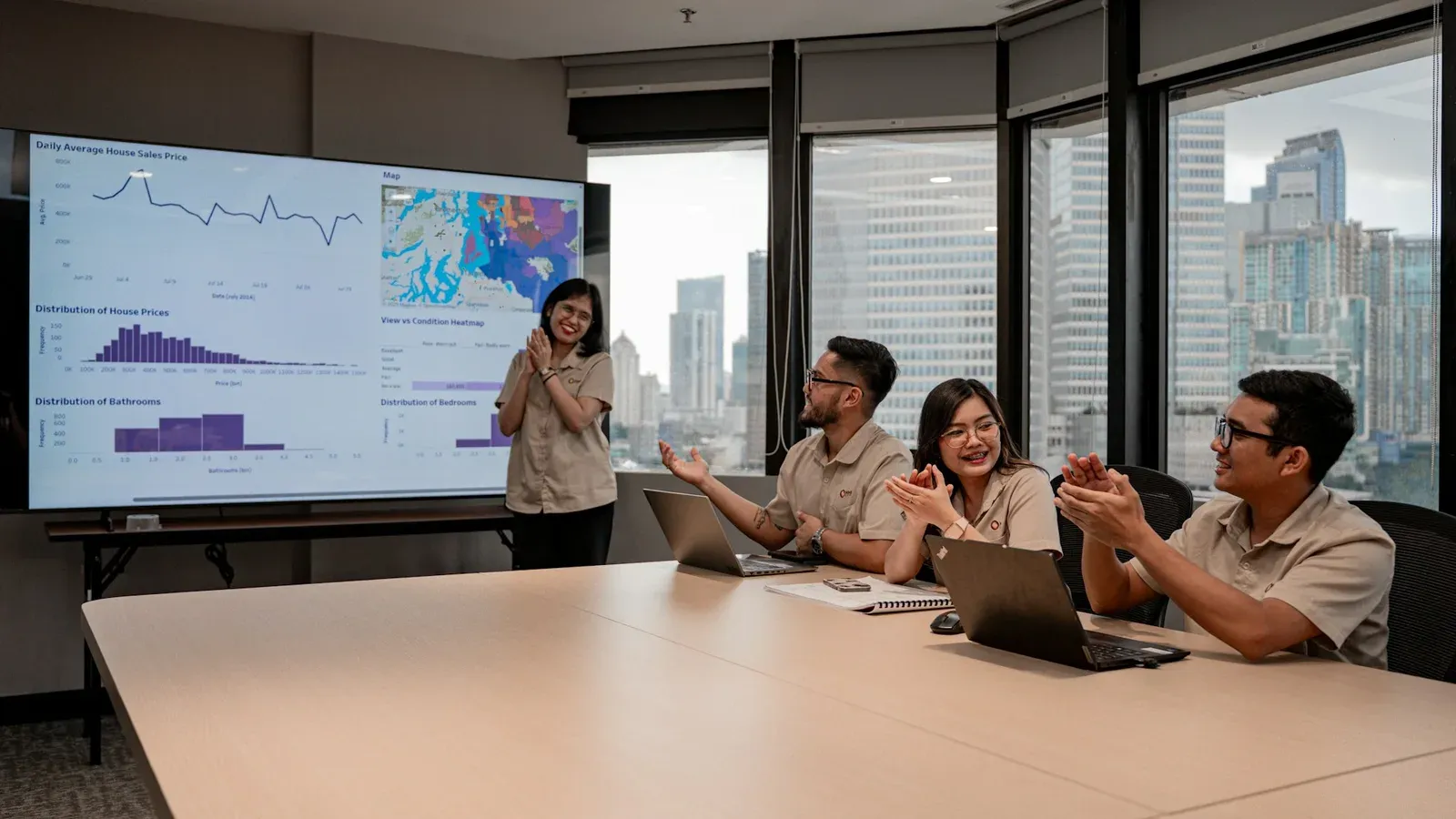 A team applauding as they review a presentation of charts during an office meeting.