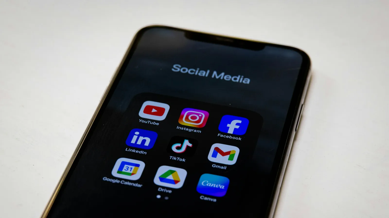 Ponsel dengan folder aplikasi media sosial: YouTube, Instagram, Facebook, LinkedIn, TikTok
